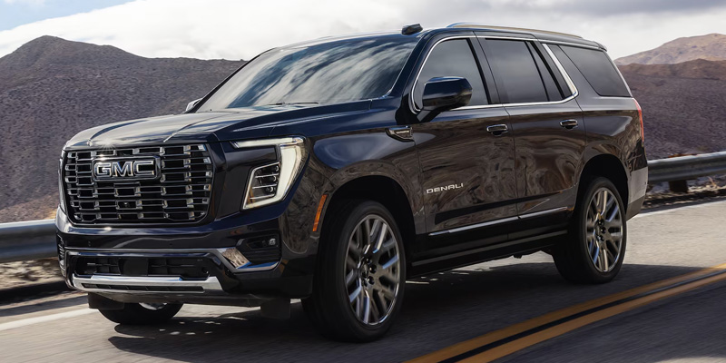 GMC Yukon XL SUV driving on a mountain road.